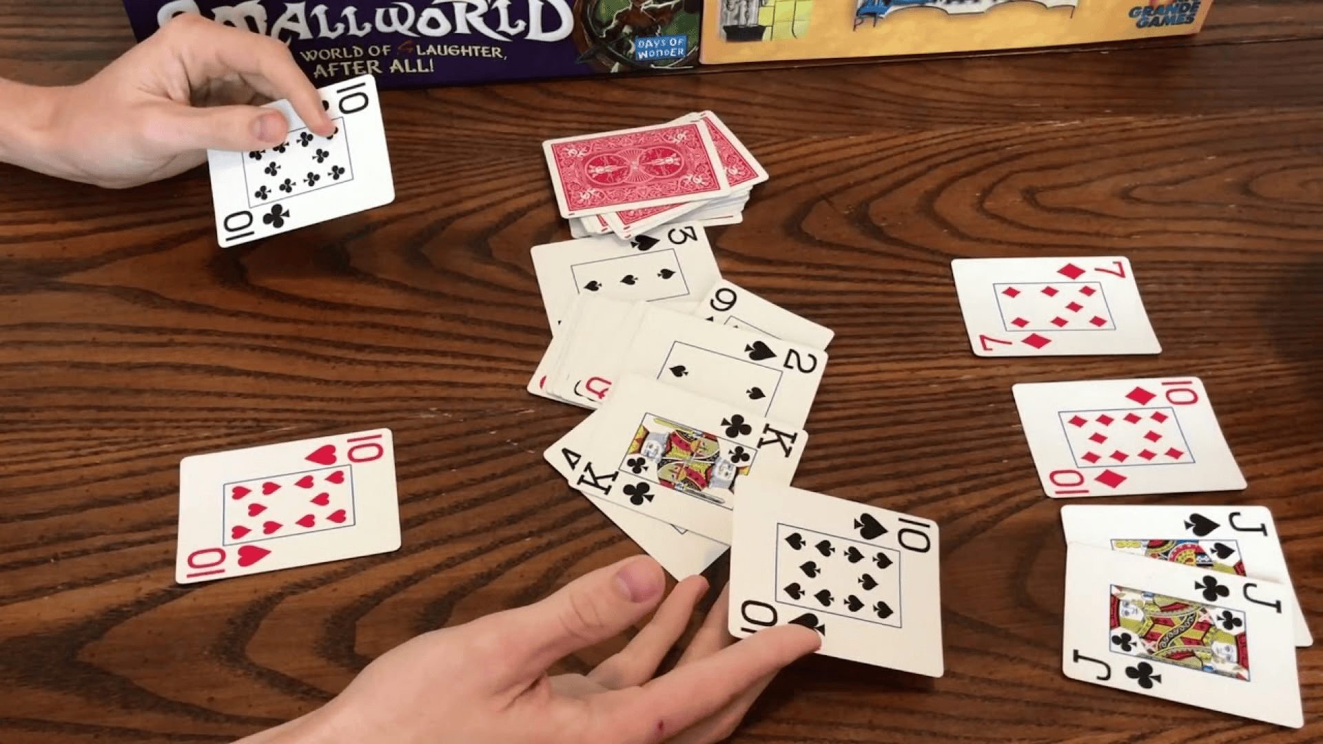 Two hands face off in a fast-paced game of Speed card game layout on a dark wooden table.