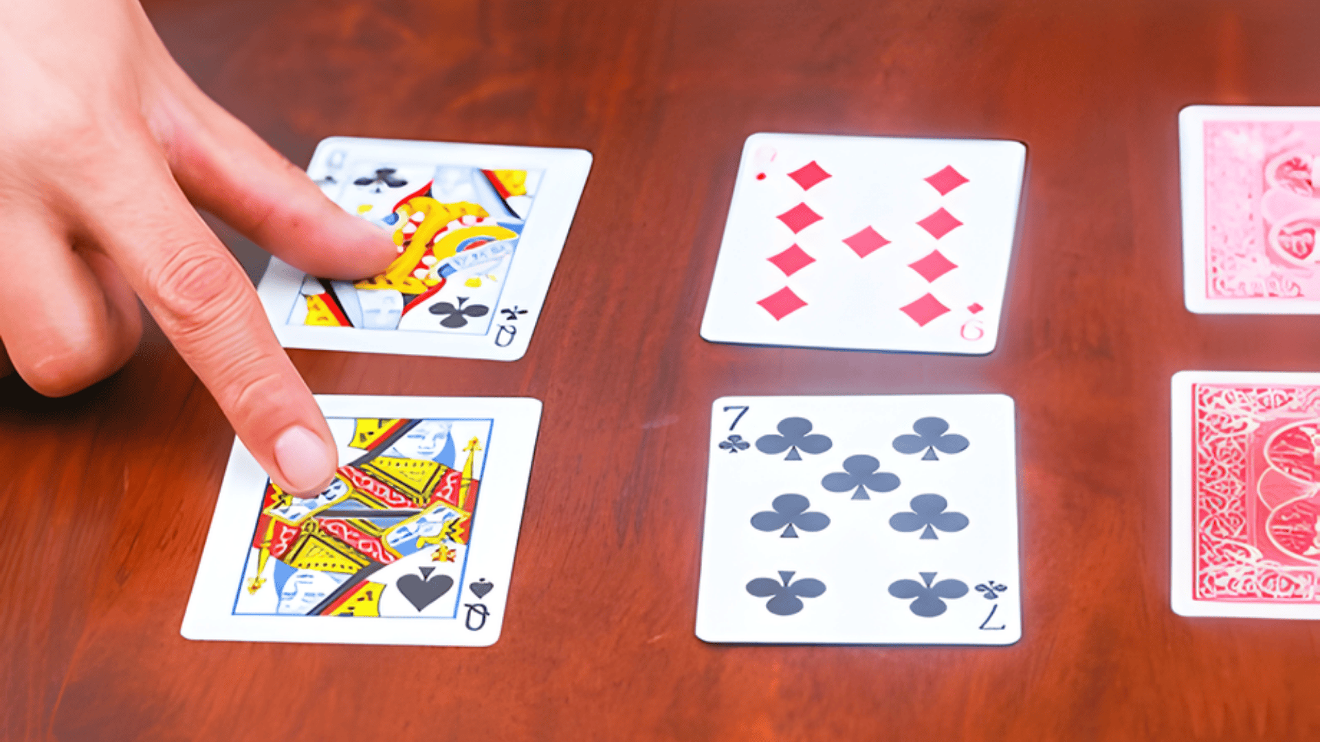 A hand slaps a pile of standard playing cards layout during a fast-paced tabletop reflex card game.